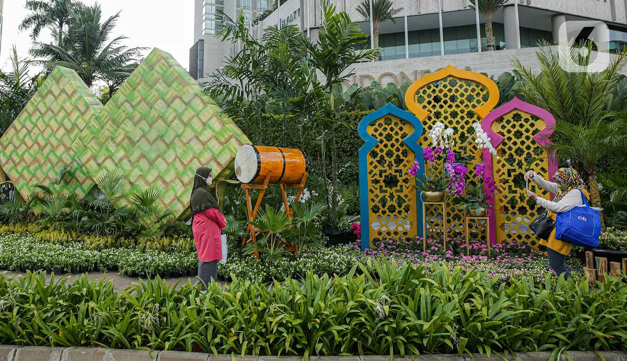 <p>Warga berfoto dengan dekorasi bertemakan Idul Fitri di kawasan Bundaran HI, Jakarta, Rabu (27/4/2022). Dekorasi berbentuk masjid, ketupat, dan bedug yang dihiasi oleh tanaman tersebut dalam rangka menyambut Idul Fitri 1443 Hijriah. (Liputan6.com/Faizal Fanani)</p>