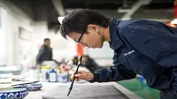 Seorang pekerja di pabrik Foxconn sedang membuuat kaligrafi (Foto: Apple)