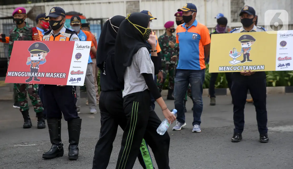 Pejalan kaki melintas saat sosialisasi penerapan protokol kesehatan PSBB di Bundaran HI, Jakarta, Minggu (13/9/2020). Kepastian pemberlakuan kembali PSBB di Jakarta masih dibahas antara Pemprov DKI dan pemerintah pusat dan akan diumumkan nanti sore. (merdeka.com/Arie Basuki)