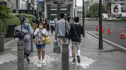 Pejalan kaki melintasi trotoar di kawasan Sudirman, Jakarta, Rabu (16/12/2020). Satgas Penanganan Covid-19 DKI Jakarta tengah membahas tentang kurva Covid-19 di wilayah Ibu Kota sembari mengkaji kebijakan WFH sebesar 75 persen bagi karyawan swasta. (Liputan6.com/Faizal Fanani)