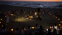 Wanita mengambil bagian dalam upacara Tashlich, di mana mereka menuliskan hal-hal yang ingin mereka lepaskan sebelum melemparkannya ke dalam api, di pantai di Tel Aviv, Israel (14/9/2021). (AP Photo/Maya Alleruzzo)