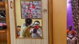 Relawan pekerja sosial Ashok Kurmi melukis wajahnya sebelum menyebarkan kesadaran tentang COVID-19 di daerah kumuh Mumbai pada 2 Juni 2021. Kurmi turun tangan memerangi virus Corona di daerah kumuh Mumbai menggunakan aksesori yang tidak biasa, yaitu kostum badut. (INDRANIL MUKHERJEE/AFP)