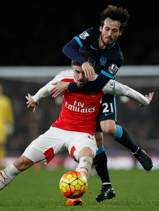 Gelandang Mancheseter City, David Silva berebut bola dengan gelandang Arsenal, Aaron Ramsey pada lanjutan liga Inggris di Stadion Emirates (21/12). Arsenal menang atas City dengan skor 2-1. (AFP PHOTO/ADRIAN DENNIS)