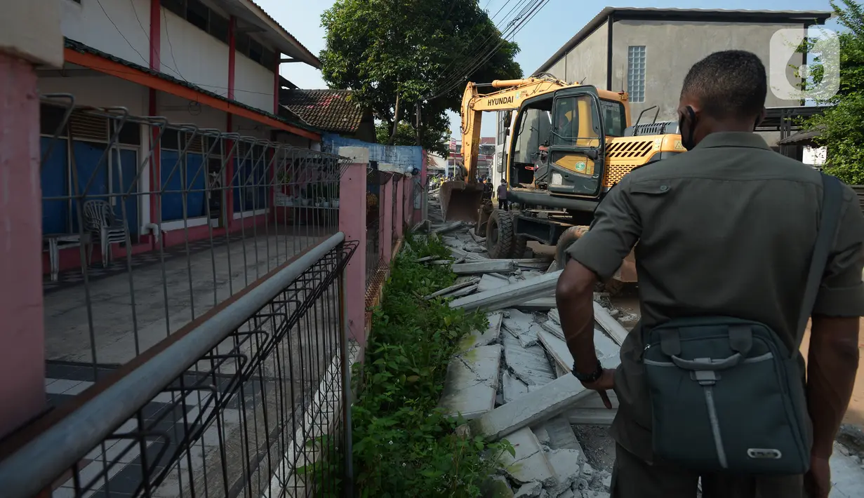 Pekerja menggunakan alat berat saat merobohkan pagar beton yang mengisolasi sejumlah warga di Jalan Akasia, Tajur Ciledug, Tangerang, Banten, Rabu ( 17/3/2021). Pagar beton yang sempat menutup akses jalan warga tersebut kini dibongkar. (merdeka.com/Imam Buhori)
