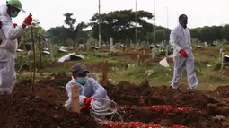 Petugas menyiram makam jenazah Covid-19 usai melakukan pemakaman dengan prosedur Covid-19 di TPU Tegal Alur, Jakarta, Minggu (3/12/2021). Sebelumnya, total kasus positif Covid-19 di Indonesia hingga Sabtu (2/12) sebanyak 758.473 kasus. (Liputan6.com/Angga Yuniar)