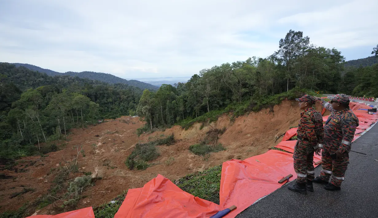 Anggota tim pemadam kebakaran dan penyelamat melihat tanah longsor di Batang Kali, Malaysia, Sabtu, 17 Desember 2022. Longsor Jumat, 16 Desember 2022, di sebuah perkemahan wisata di Malaysia menyebabkan lebih dari selusin orang tewas dan pihak berwenang mengatakan belasan orang lainnya dikhawatirkan terkubur di lokasi di sebuah pertanian organik di luar ibu kota Kuala Lumpur. (AP Photo/Vincent Thian)