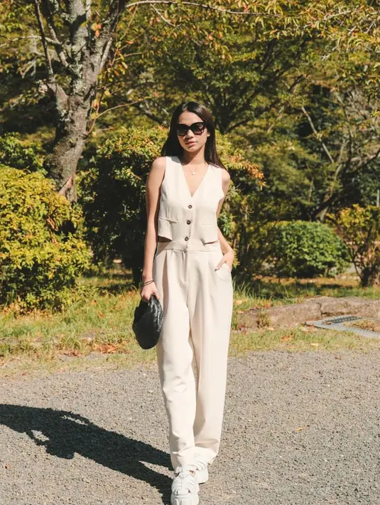 Kali ini Azizah Salsha tampil minimalis dengan setelan vest top dan celana panjang bernuansa broken white. Ia tampak menyempurnakan gayanya dengan handbag hitam, sunglasses, dan sneakers putih. [Foto: Instagram/azizahsalsha_]