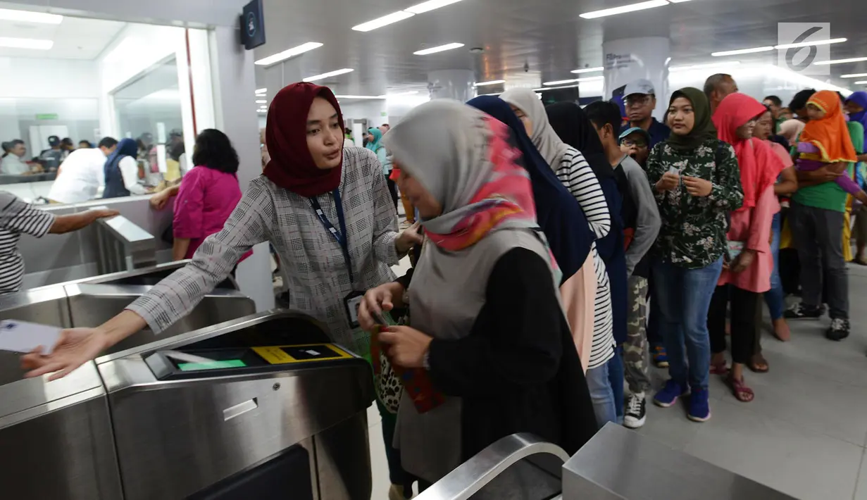 Petugas membantu calon penumpang melakukan tap kartu saat akan menggunakan layanan transportasi Moda Raya Terpadu (MRT) di Stasiun Bundaran HI, Jakarta, Rabu (3/4). Meski sudah tidak digratiskan, warga tetap antusias menjajal MRT. (merdeka.com/Imam Buhori)