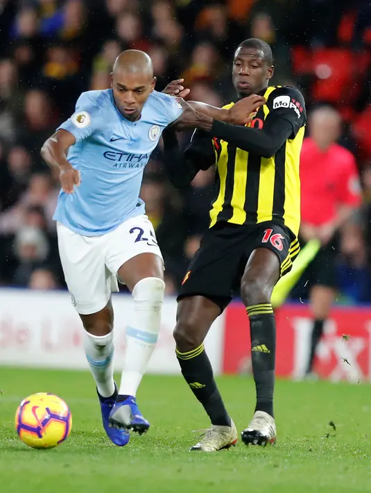Gelandang Manchester City, Fernandinho menggiring bola dari kawalan pemain Watford Abdoulaye Doucoure selama pertandingan lanjutan Liga Inggris di stadion Vicarage Road (4/12). City menang tipis atas Watford 2-1. (AP Photo/Frank Augstein)