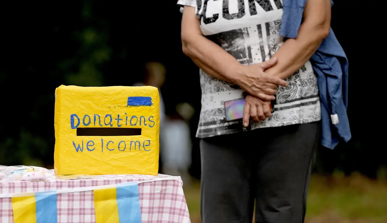 Seorang perempuan menunggu di dekat kotak sumbangan pada perayaan Hari Kemerdekaan Ukraina di sebuah perayaan di Chichester, Inggris selatan, Sabtu, 27 Agustus 2022. Chichester dinobatkan sebagai daerah paling dermawan di negara itu untuk menampung pengungsi Ukraina. (AP Photo/Frank Augstein)