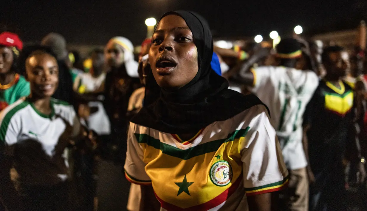 Reaksi seorang suporter Senegal menonton pertandingan babak 16 besar Piala Dunia 2022 saat tim kesayangan mereka melawan Inggris di Qatar, lewat layar video yang dipsang di fan zone di Dakar, Senin (5/12/2022) dini hari WIB. Senegal ditaklukkan Inggris dengan skor 0-3. (Photo by JOHN WESSELS / AFP)