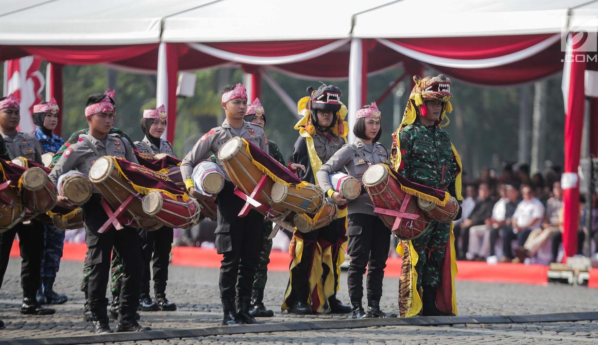 Prajurit TNI dan Polri berkolaborasi memainkan rampak gendang dalam HUT ke-73 Bhayangkara di Monas, Jakarta, Rabu (10/7/2019). HUT Bhayangkara ke-73 ini bertemakan ‘Dengan semangat Promoter, pengabdian Polri, untuk masyarakat, bangsa, dan negara. (Liputan6.com/Faizal Fanani)