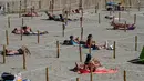 Orang-orang berjemur di Sunset Beach dengan area terpisah untuk mematuhi jaga jarak di La Grande-Motte, Prancis, Selasa (26/5/2020). Cara ini dilakukan pemerintah Prancis yang mengaku mencontohnya dari otoritas di Spanyol yang telah terlebih dahulu memperkenalkannya (Pascal GUYOT/AFP)