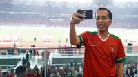 Presiden Jokowi membuat vlog saat menyaksikan laga final Piala Presiden 2018 antara Persija Jakarta vs Bali United di Stadion Utama Gelora Bung Karno, Sabtu (17/2). Jokowi terlihat menggunakan busana kasual. (Liputan6.com/Pool/Biro Pers Setpres)