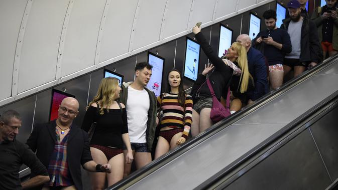 Orang-orang menggunakan eskalator saat ambil bagian dalam 'No Trousers On The Tube Day' atau No Pants Subway Ride di London Underground,  pusat Kota London, Minggu (12/1/2020). New York menjadi kota pertama yang menghajat acara naik kereta tanpa celana ini sejak tahun 2002. (DANIEL LEAL-OLIVAS/AFP)