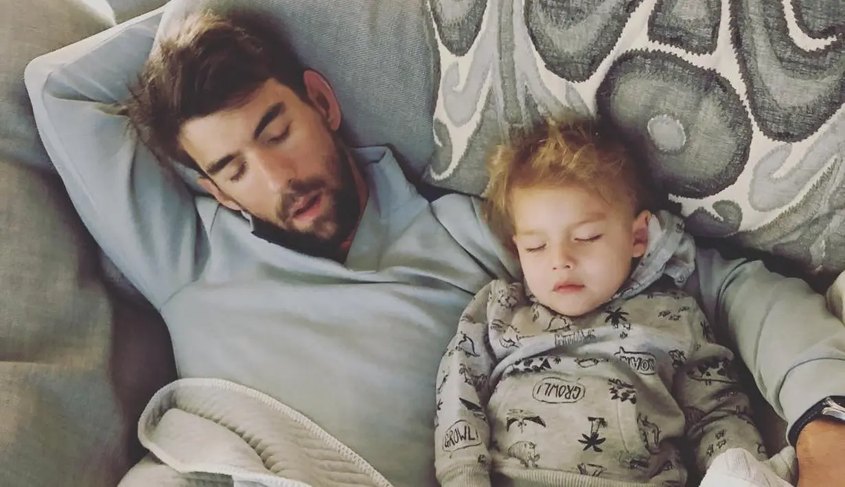 Nicole Phelps mengunggah foo suaminya, Michael Phelps saat tertidur lelap di sofa bersama dengan anaknya, Boomer. (instagram/mrs.nicolephelps)