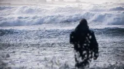 Seorang pria melihat kota Penmarch dari pantai La Torche di Plomeur, Prancis barat (28/12/2020). Badai Bella pun dilaporkan menyebabkan gangguan pada perjalanan udara. (AFP/Loic Venance)