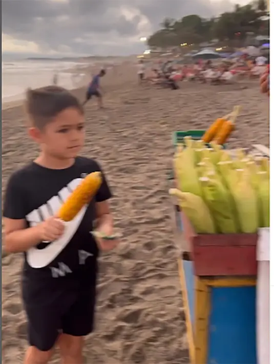 Saat bermain ke pantai, El Barack langsung menuju tukang jagung bakar. Meski kedua orang tuanya dikenal kaya, El tampak santai membeli jajanan kaki lima yang menggunakan gerobak. [Instagram/inijedar]