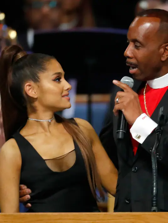 Ariana Grande mendengarkan Uskup Charles H. Ellis III berbicara dalam upacara pemakaman Aretha Franklin di Greater Grace Temple, Detroit, Michigan, AS, Jumat (31/8). Uskup Charles dituding meraba bagian dada Ariana Grande. (AP Photo/Paul Sancya)