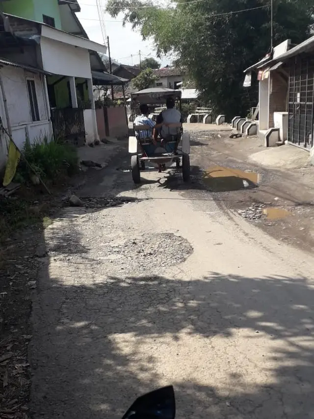 Akibat akses jalan rusak, nampak sebuah delman lebih memilih jalan dengan pelan untuk memilih jalan menuju Taman Cikembulan.