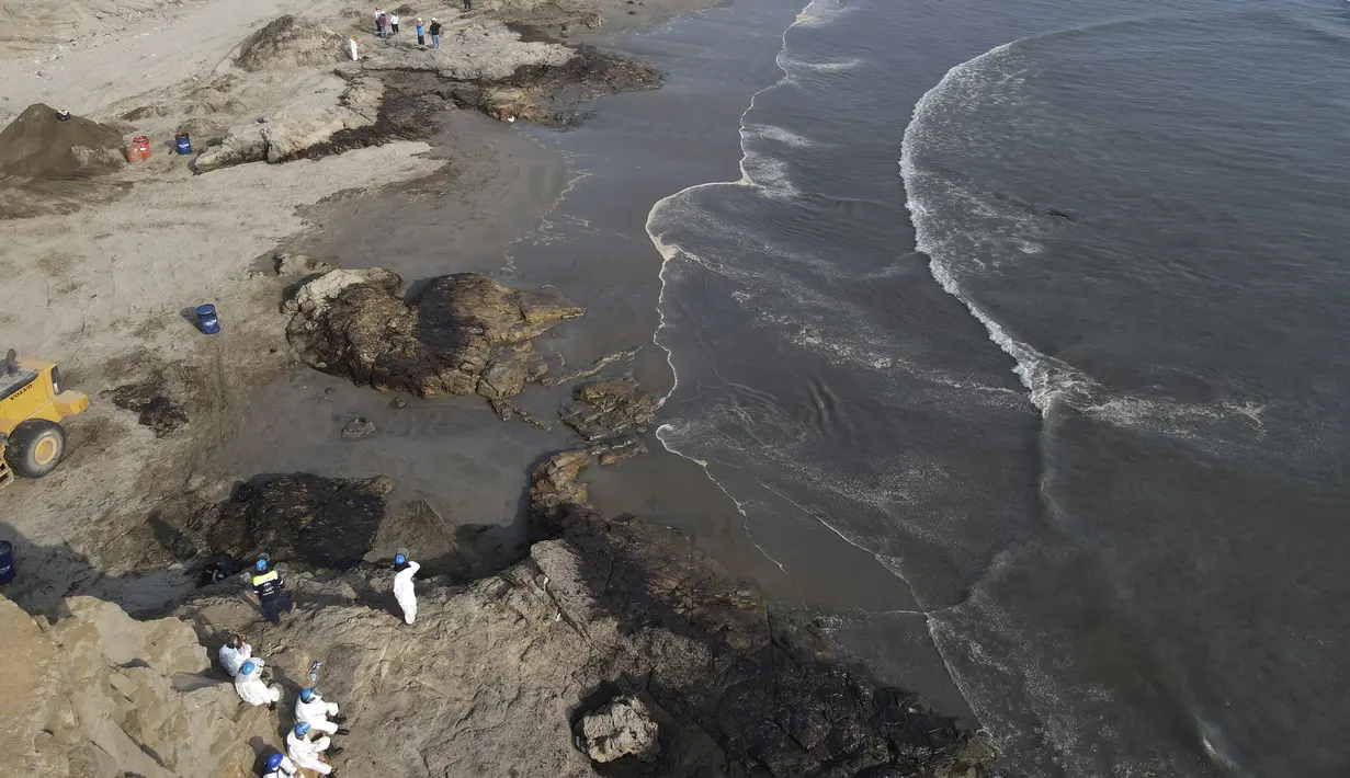 Pekerja membersihkan tumpahan minyak di pantai Cavero di Ventanilla, Callao, Peru, Senin (17/1/2022). Tumpahan akibat gelombang tsunami yang dipicu letusan gunung api bawah laut di Tonga ini dikendalikan dalam beberapa jam namun, proses pembersihan masih terus berlangsung. (AP Photo/Martin Mejia)