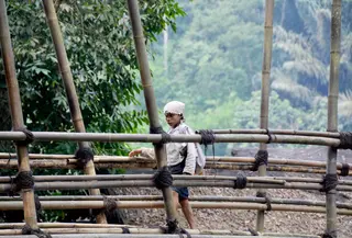 Seorang masyarakat Baduy Dalam melintas di jambatan bambu yang berada di kawasan Baduy Luar, Sabtu, 24/8/2024. (Syahrul Rahmat)