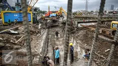Para pekerja sedang memasangkan besi yang digunakan untuk pondasi jalan di kawasan Latumenten, Jakarta, Senin (05/12). Perbaikan jalan dengan mengganti pondasi baru tersebut guna memperkuat ketahanan badan jalan. (Liputan6.com/Faizal Fanani)