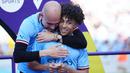 Pelatih Manchester City, Pep Guardiola, memeluk Rico Lewis saat perayaan gelar juara Liga Inggris di Stadion Etihad, Manchester (21/5/2023). (AP Photo/Jon Super)