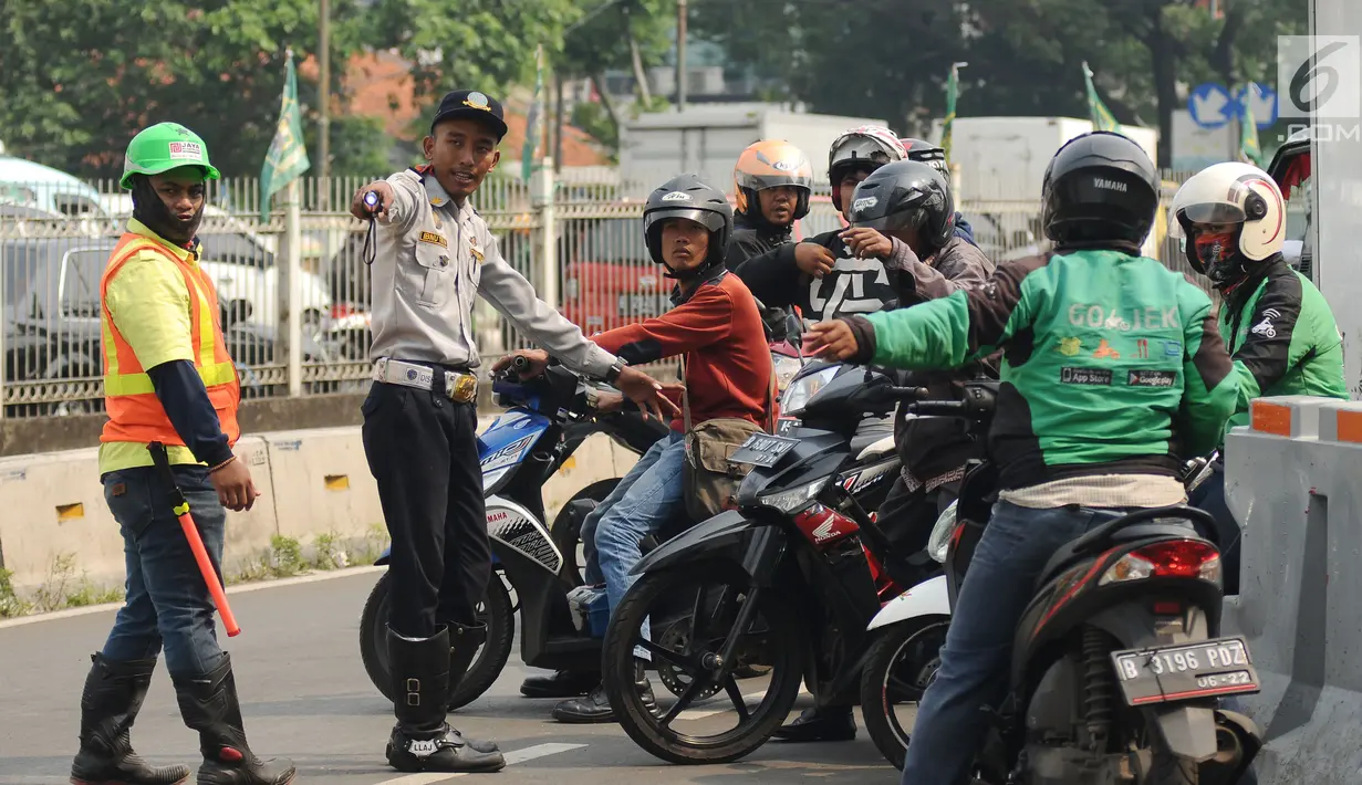 Petugas mensosialisasikan uji coba pengalihan arus lalu lintas di pertigaan Jalan Pramuka Sari II, Jakarta, Jumat (21/7). Pengalihan arus lalu lintas terkait pembangunan underpass Matraman. (Liputan6.com/Helmi Fithriansyah)