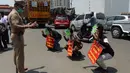 Sejumlah pria mengenakan topeng bergambar virus corona dan memegang plakat bertuliskan "Jangan keluar, jangan mendekati corona" sebagai hukuman karena keluar rumah selama pemberlakukan penguncian wilayah (lockdown) di Chennai, India, Rabu (1/4/2020). (Arun SANKAR / AFP)