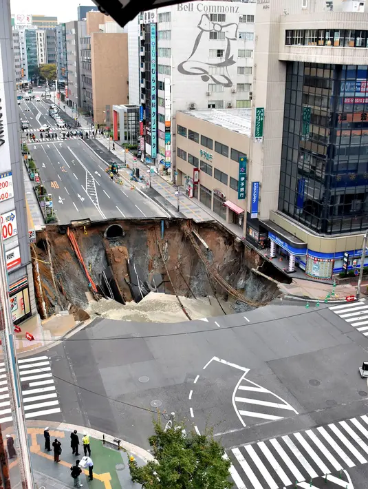 Penampakan lubang raksasa atau biasa disebut sinkhole yang tiba-tiba muncul di persimpangan dekat Stasiun Hakata, Fukuoka, Jepang, Selasa (8/11). Insiden itu mengakibatkan lalu lintas terputus, pemadaman listrik serta kebocoran gas. (Kyodo/via REUTERS)