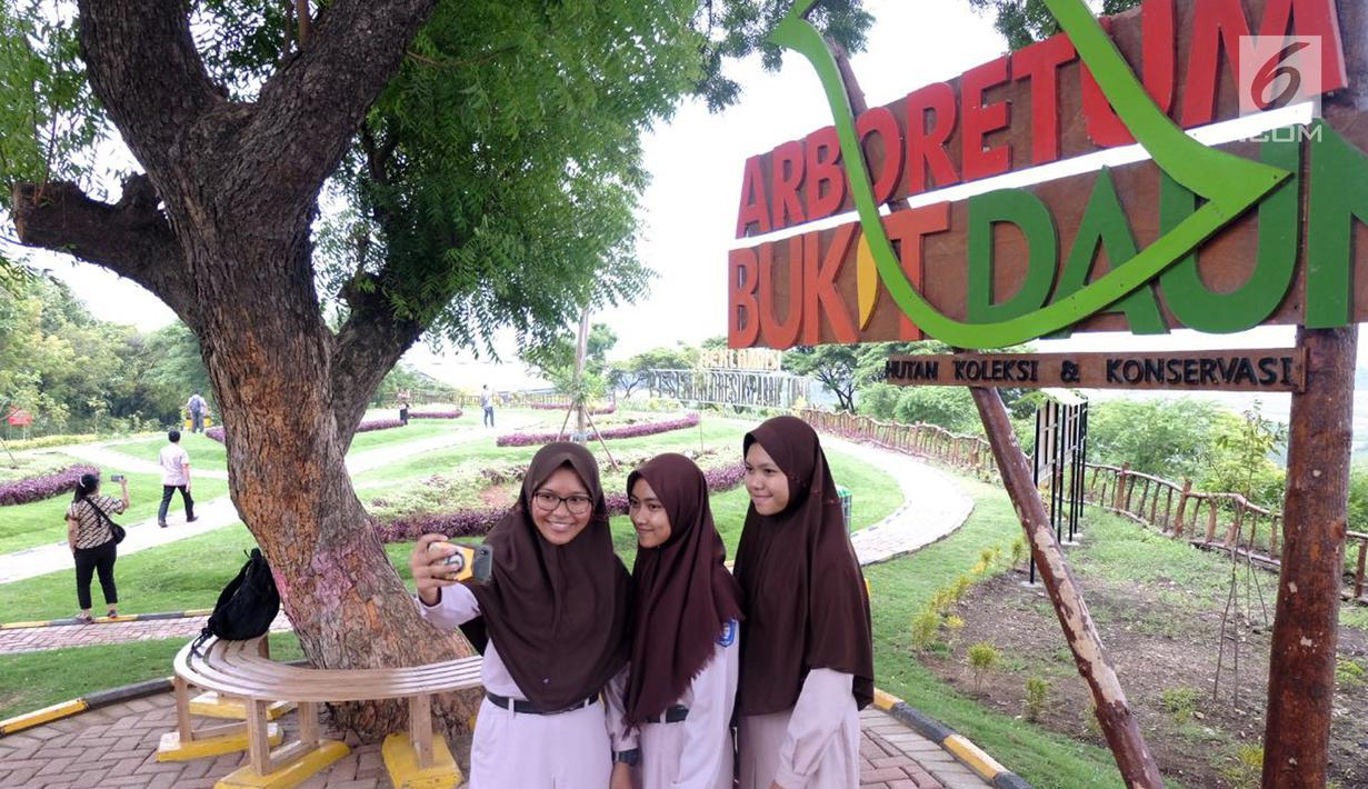 Siswa sedang berswafoto di objek wisata taman bukit daun Desa Sumberarum, Tuban, Jawa Timur, Kamis (22/2). Taman yang menempati lahan seluas 1.000 m2 dibangun di atas lahan bekas tambang batu kapur Semen Indonesia. (Liputan6.com/Pool/Eko)
