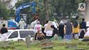 Keluarga dan kerabat menyaksikan pemakaman jenazah dengan protokol COVID-19 dari luar area di TPU Srengseng Sawah, Jakarta, Kamis (21/1/2021). Sebagian lahan TPU Srengseng Sawah yang dijadikan lokasi pemakaman jenazah Covid-19 kini hanya tersisa 79 petak makam. (Liputan6.com/Helmi Fithriansyah)