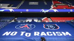 Petugas stadion memasang spanduk raksasa bertuliskan "NO TO RACISM" menjelang laga lanjutan Liga Champions Grup H antara PSG melawan Istanbul Basaksehir di Parc des Princes Stadium, Selasa (8/12/2020). (AFP/Franck Fife)