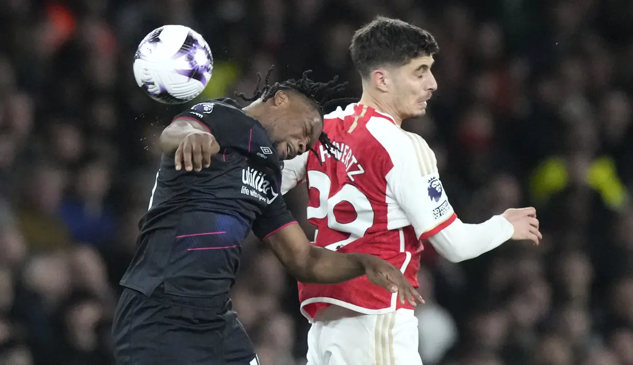 Bek Luton Town, Teden Mengi (kiri) berduel udara dengan gelandang Arsenal, Kai Havertz pada laga pekan ke-31 Premier League 2023/2024 di Emirates Stadium, London, Rabu (3/4/2024) malam. (AP Photo/Frank Augstein)
