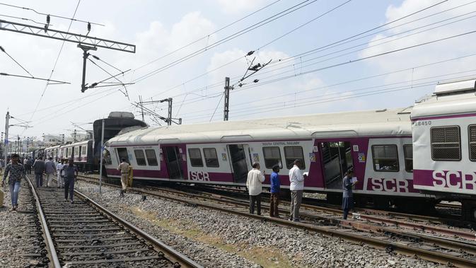 Sejumlah penumpang berdiri di samping gerbong kereta surburban yang bertabrakan dengan kereta ekspres antarkota di Stasiun Kereta Api Kachiguda di Hyderabad, India (11/9/2019). Sekitar 12 orang terluka akibat kecelakaan tersebut. (AFP Photo/Noah Seelam)