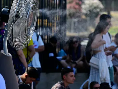 Sebuah kipas angin menyemprotkan air di sepanjang gerbang Colosseum, Roma untuk menyegarkan para turis pada tanggal 11 Juli 2024. (Tiziana FABI/AFP)