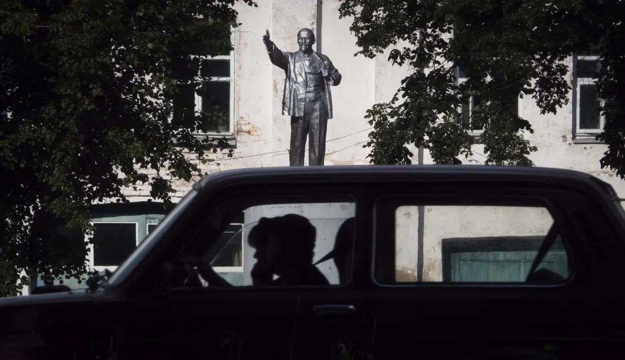 Orang bepergian dengan mobil melewati patung pendiri Uni Soviet Vladimir Lenin di kota Tutayev yang terletak di Sungai Volga, 300 km (186 mil) timur laut Moskow, Rusia, Kamis (6/8/2020). (AP Photo / Dmitri Lovetsky)