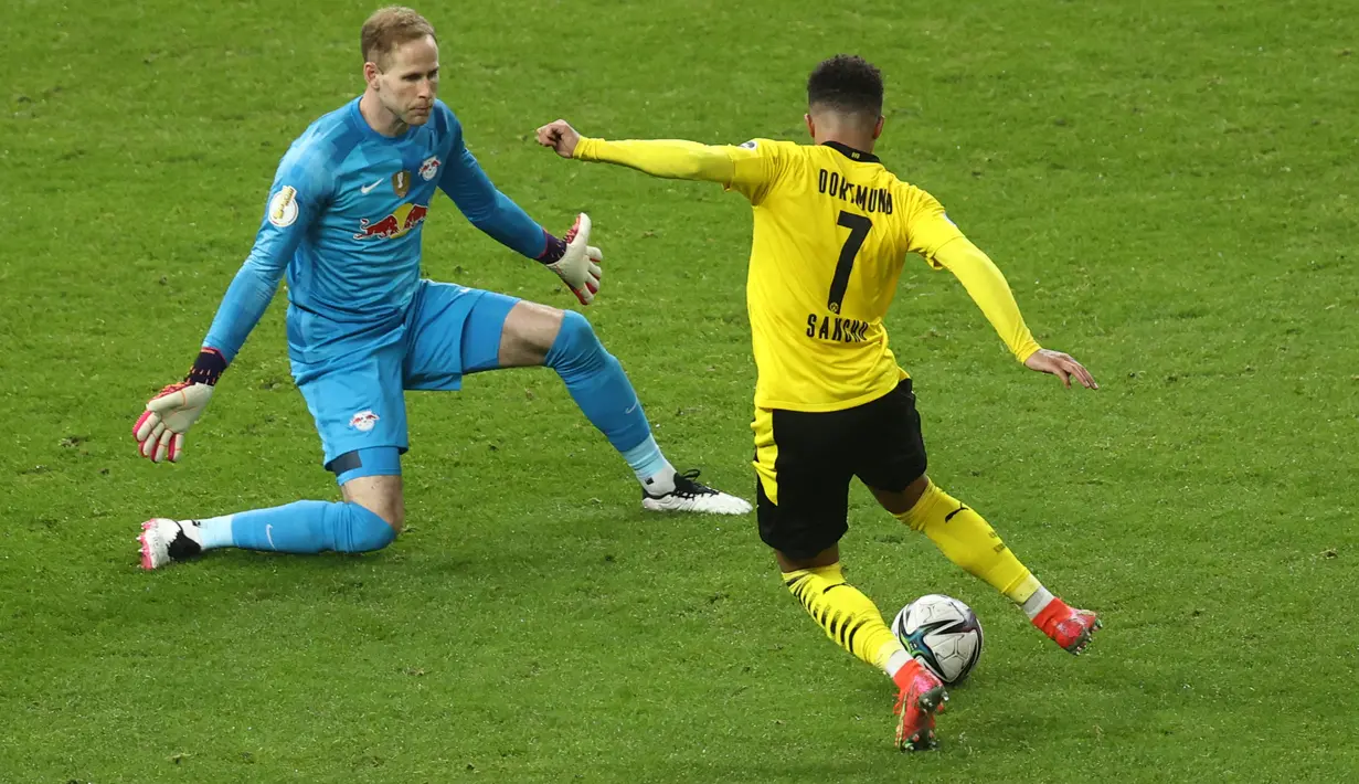 Gelandang Dortmund, Jadon Sancho berusaha melewati kiper RB Leipzig, Peter Gulacsi dalam pertandingan divisi satu Bundesliga di Berlin pada 13 Mei 2021. Selanjutnya, pemain Inggris itu tinggal menjalani tes medis dan diresmikan sebagai pemain baru MU. (AFP/ Pool/Maja Hitij)