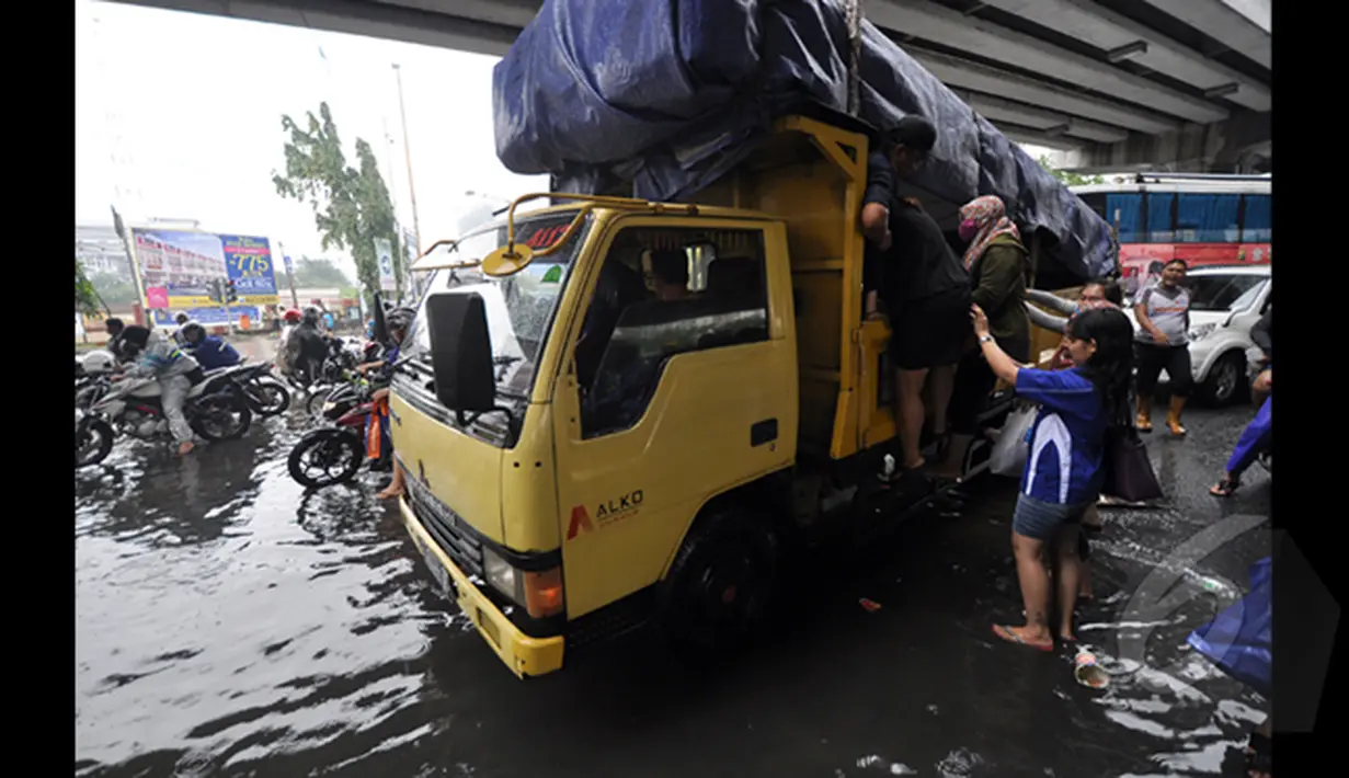 Tampak seorang wanita berusaha menaiki truk yang lewat untuk melalui banjir Jakarta, Senin (6/2/2015).  Hujan yang turun sejak malam hingga kini membuat sejumlah ruas jalan di ibukota banjir. (Liputan6.com/Faizal Fanani)