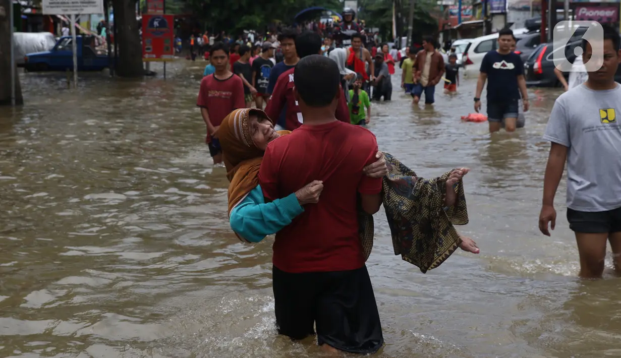 Seorang nenek digendong saat melintasi banjir yang menggenangi Jalan KH Hasyim Ashari, Tangerang, Banten, Kamis (2/1/2020). Banjir yang menggenangi jalan penghubung Jakarta- Tangerang tersebut mulai surut dan sudah bisa dilintasi pejalan kaki. (Liputan6.com/Angga Yuniar)