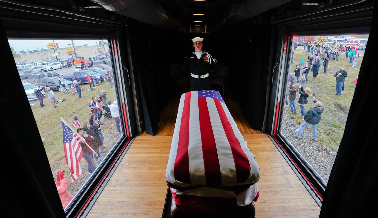 Anggota militer menjaga peti jenazah Presiden ke-41 AS George HW Bush dalam sebuah kereta saat melintasi Magnolia, Texas, Kamis (6/12). Kereta pembawa jenazah George HW Bush berangkat dari Houston menuju College Station. (AP Photo/David J. Phillip, Pool)