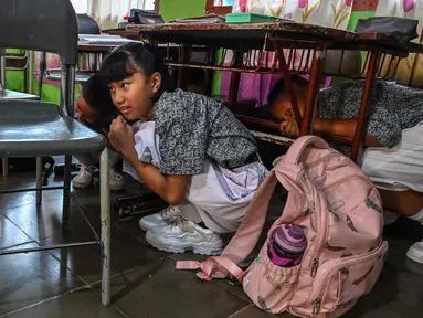 Para siswa saat ambil bagian dalam latihan gempa bumi dalam acara simulasi evakuasi mandiri dalam rangka peringatan bulan pengurangan risiko bencana di Banda Aceh, Rabu (9/10/2024). (CHAIDEER MAHYUDDIN/AFP)