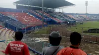 Orang-orang memeriksa kerusakan setelah tragedi kerusuhan pada pertandingan sepak bola antara Arema Vs Persebaya di Malang, Jawa Timur, Minggu (2/10/2022). Korban meninggal dunia dalam kejadian tersebut bertambah dua orang menjadi 129 orang. (AP Photo/Hendra Permana)