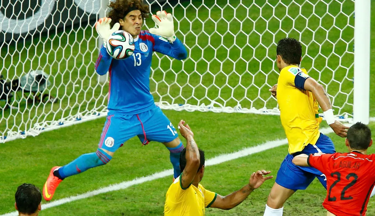 Penjaga gawang Meksiko, Guillermo Ochoa (kiri), berhasil menahan bola hasil tandukan kepala Thiago Silva (Brasil) saat berlaga di babak penyisihan Piala Dunia Grup A di Estadio Castelao, Brasil, (18/6/2014). (REUTERS/Mike Blake)