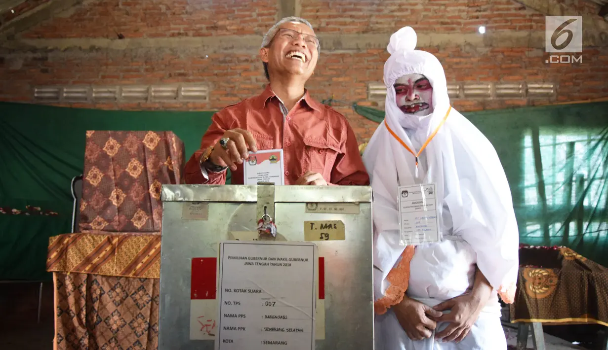 Warga ditemani petugas berkostum pocong memasukkan surat suara setelah mencoblos pada Pilkada Serentak 2018 di TPS 7 Randusari, Kota Semarang, Rabu (27/6). TPS tersebut didekor dengan suasana menyeramkan dan berbau mistis. (Liputan6.com/Gholib)