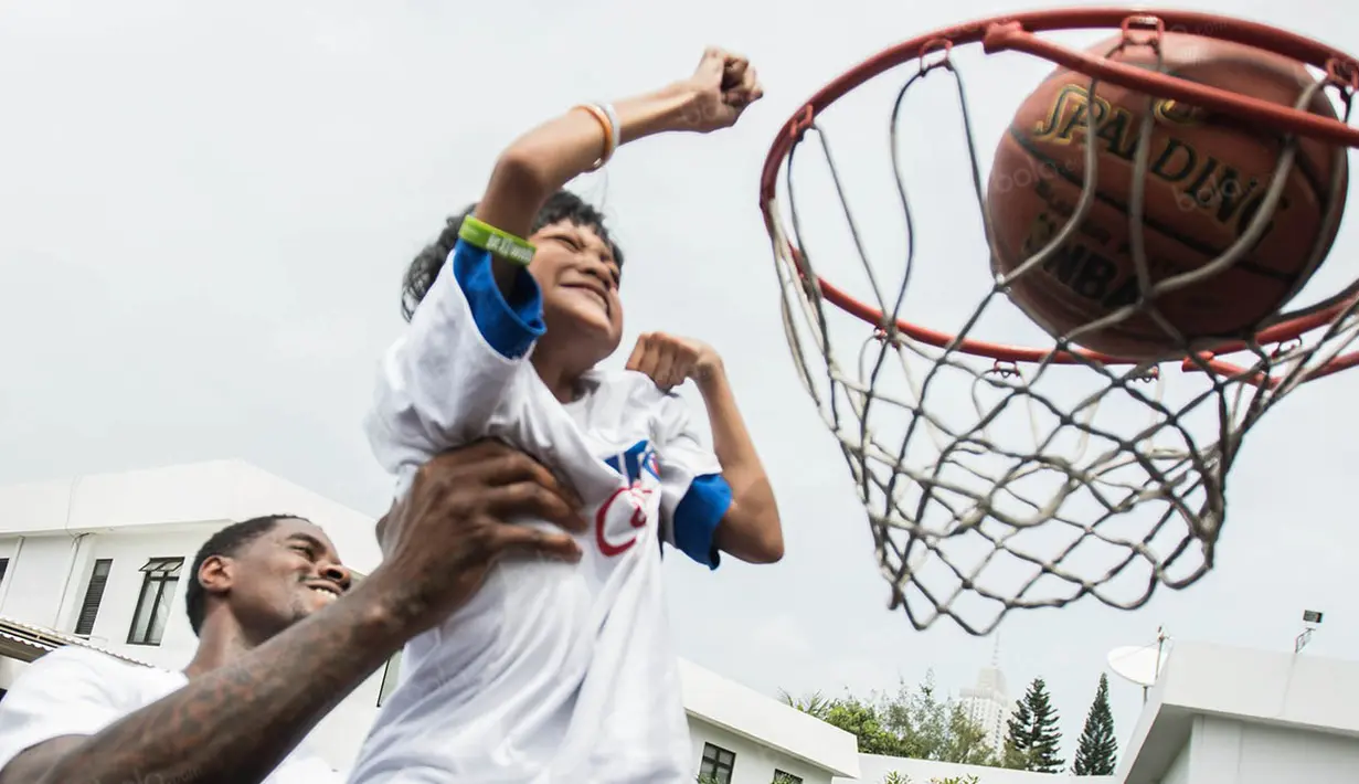 Pebasket NBA asal klub Charlotte Hornets, Marvin Williams, menggendong seorang anak penyandang disabilitas. (Bola.com/Vitalis Yogi Trisna)