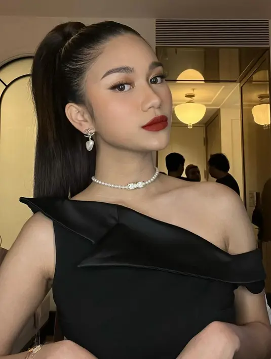 Disempurnakan dengan pulasan makeup bold karya MUA @ochiipramita, yang berfokus pada aplikasi lipstik nuansa bold maroon pada bibirnya. Sementara rambutnya ditata bergaya ponytail. [@ochiipramita/@azizahsalsha_]