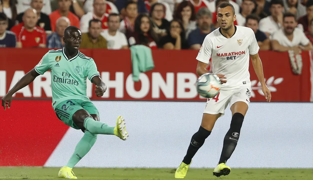Bek Real Madrid, Ferland Mendy (kiri) mengumpan bola dari kawalan pemain Sevilla, Joan Jordan selama pertandingan lanjutan La Liga Spanyol di stadion Ramon Sanchez Pizjuan di Seville (22/9/2019). Real Madrid menang tipis atas Sevilla 1-0. (AP Photo/Miguel Morenatti)