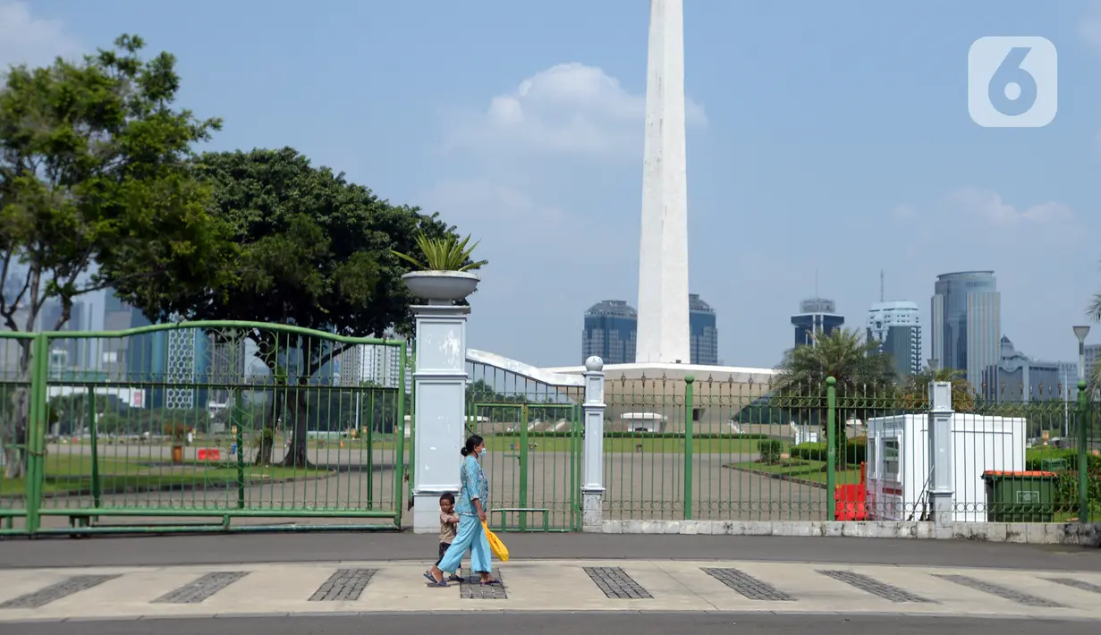 Warga berjalan di depan pagar Monumen Nasional (Monas), Jakarta, Sabtu (15/5/2021). Warga kecewa lantaran tempat wisata tersebut ditutup, padahal mereka datang untuk menikmati libur Idul Fitri 1442 Hijriah. (merdeka.com/Imam Buhori)